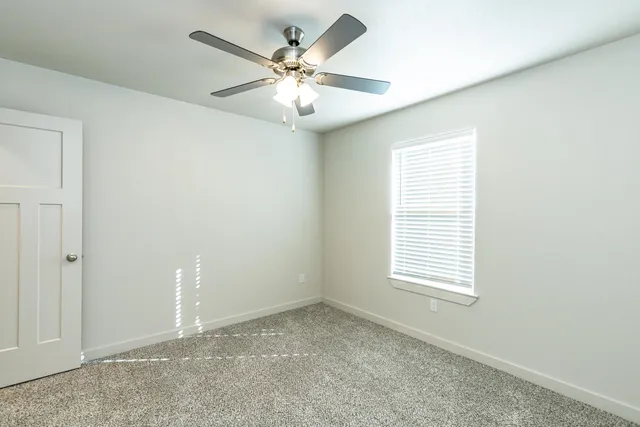 an empty room with a window and a fan
