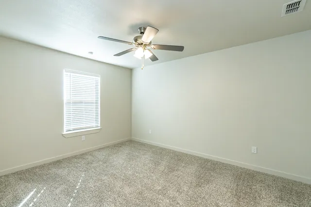 an empty room with windows and fan