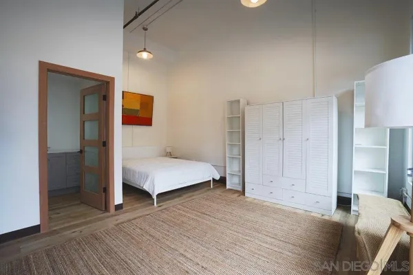 a bedroom with a bed and a potted plant on dresser