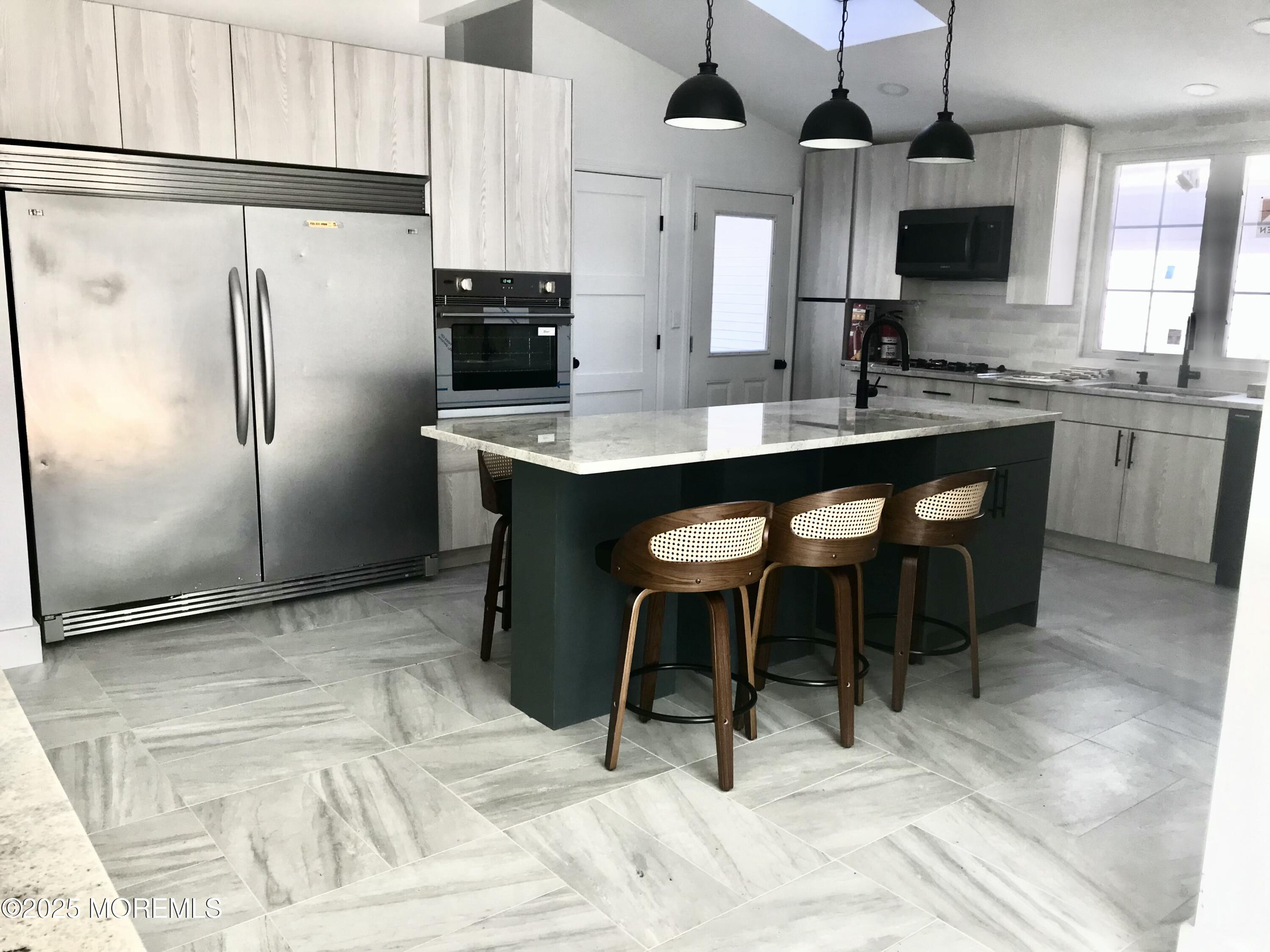 11 Lakeview Road Deal, NJ 07723 - Photo 13 of 15 a kitchen with stainless steel appliances kitchen island granite countertop a refrigerator a sink a stove and chairs