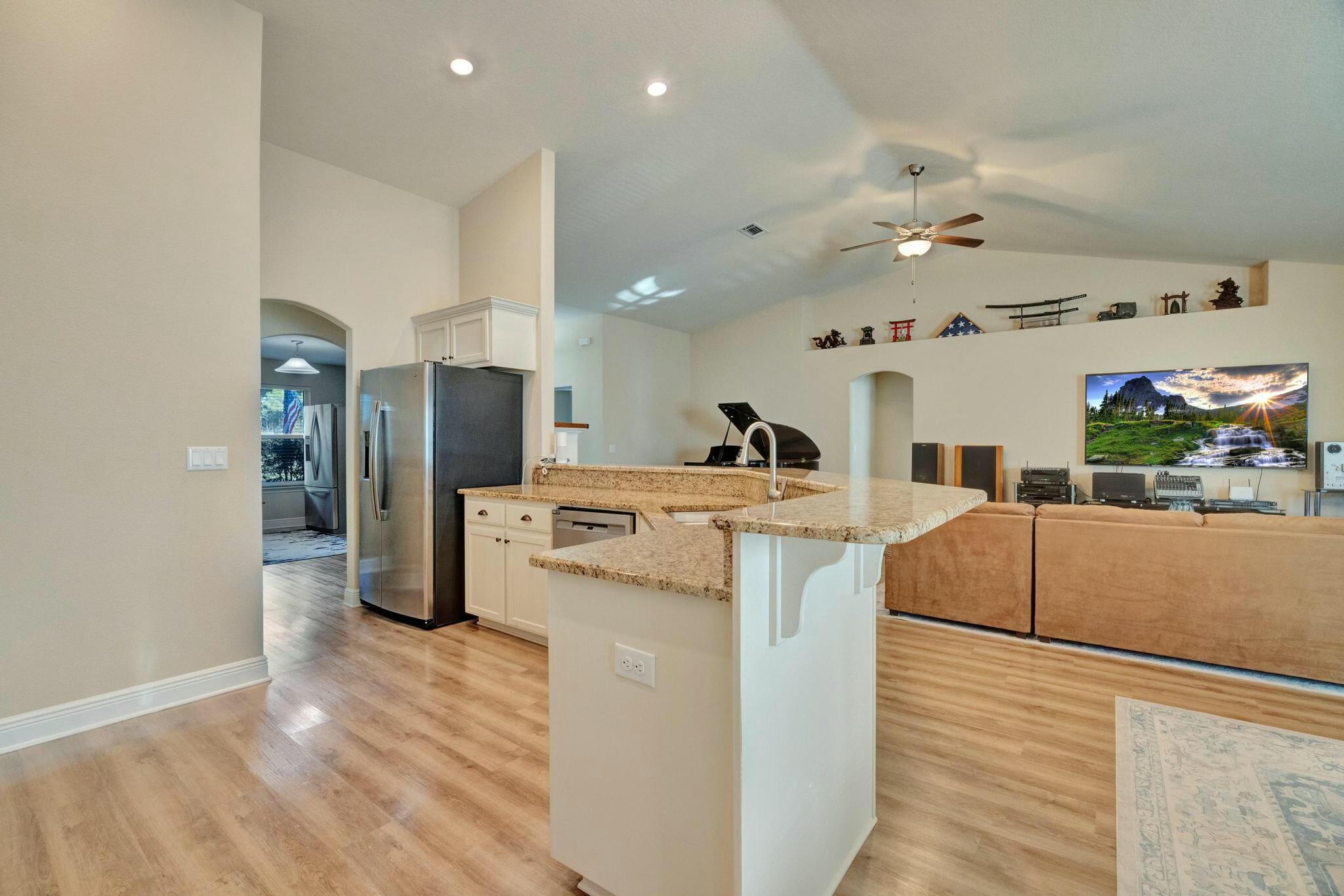 3278 Main Street Navarre, FL 32566 - Photo 13 of 43 a living room with stainless steel appliances kitchen island a sink and a refrigerator