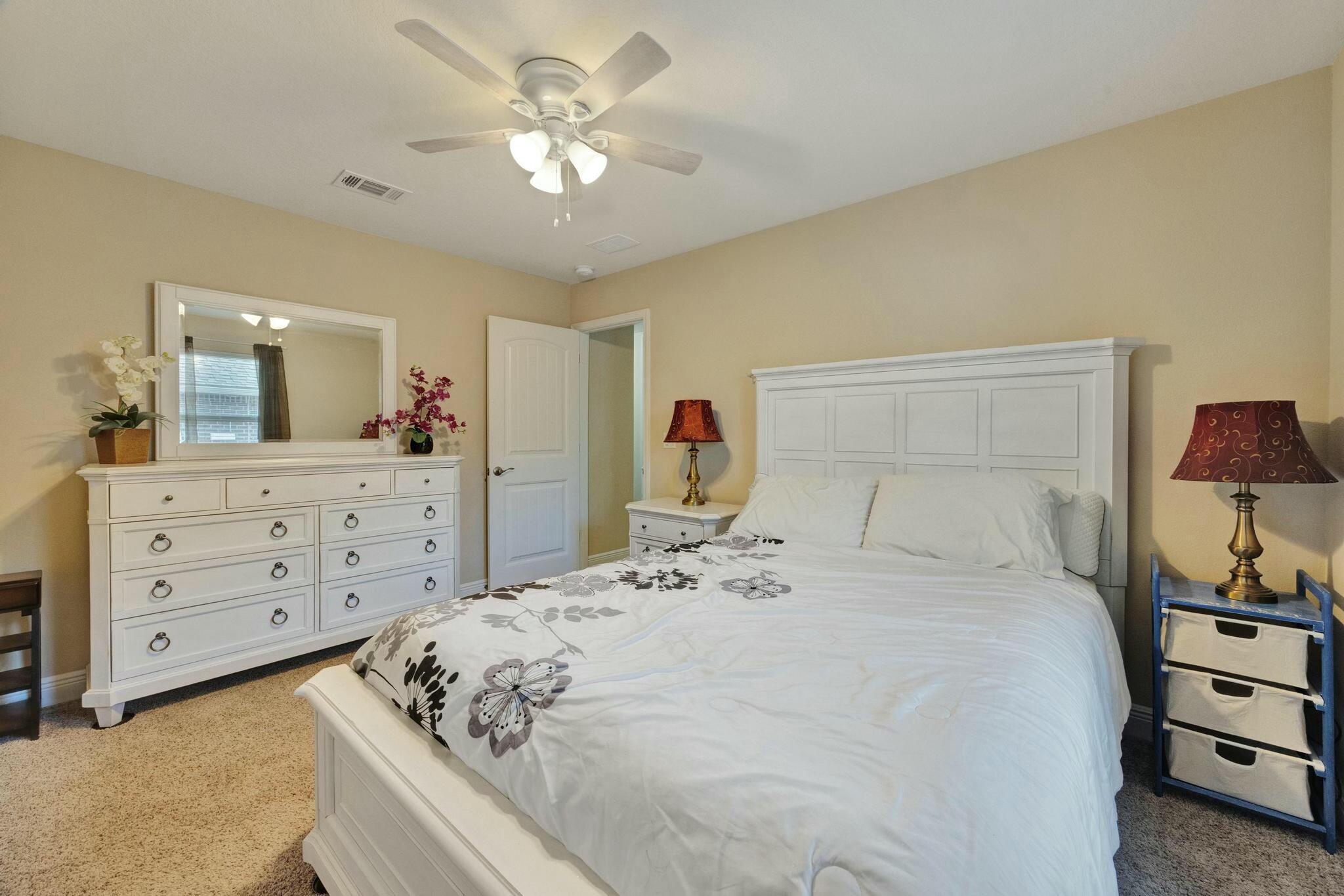 3278 Main Street Navarre, FL 32566 - Photo 29 of 43 a bedroom with a bed a chandelier and a dresser