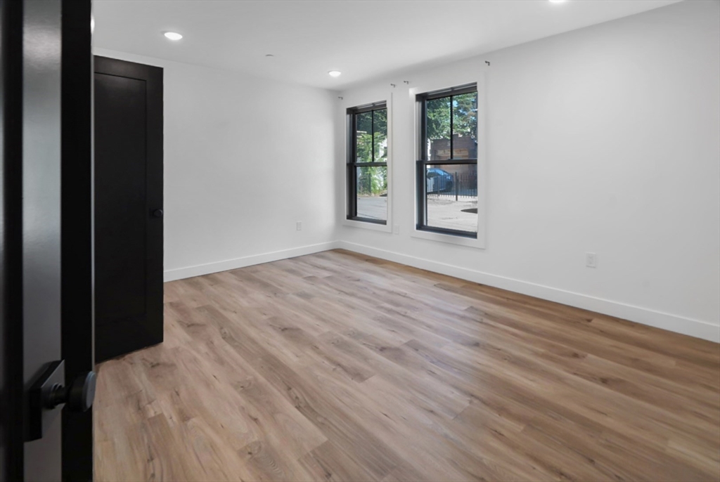 173 Magnolia Street, Unit 1 Boston, MA 02125 - Photo 6 of 9 an empty room with wooden floor and windows