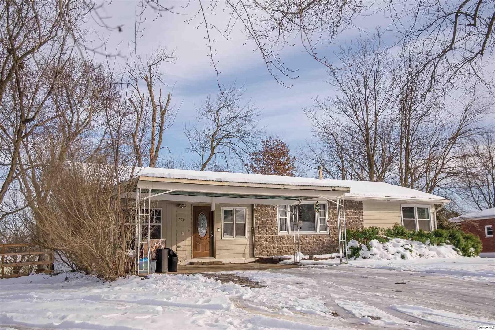 a front view of a house with a garden and trees
