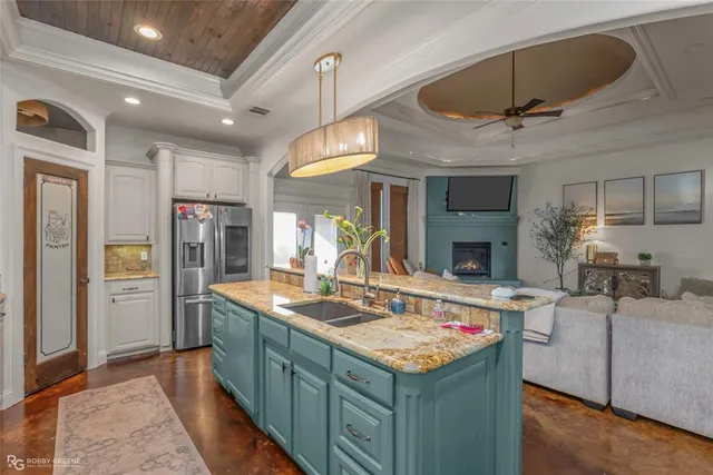 a kitchen with kitchen island granite countertop a sink and refrigerator