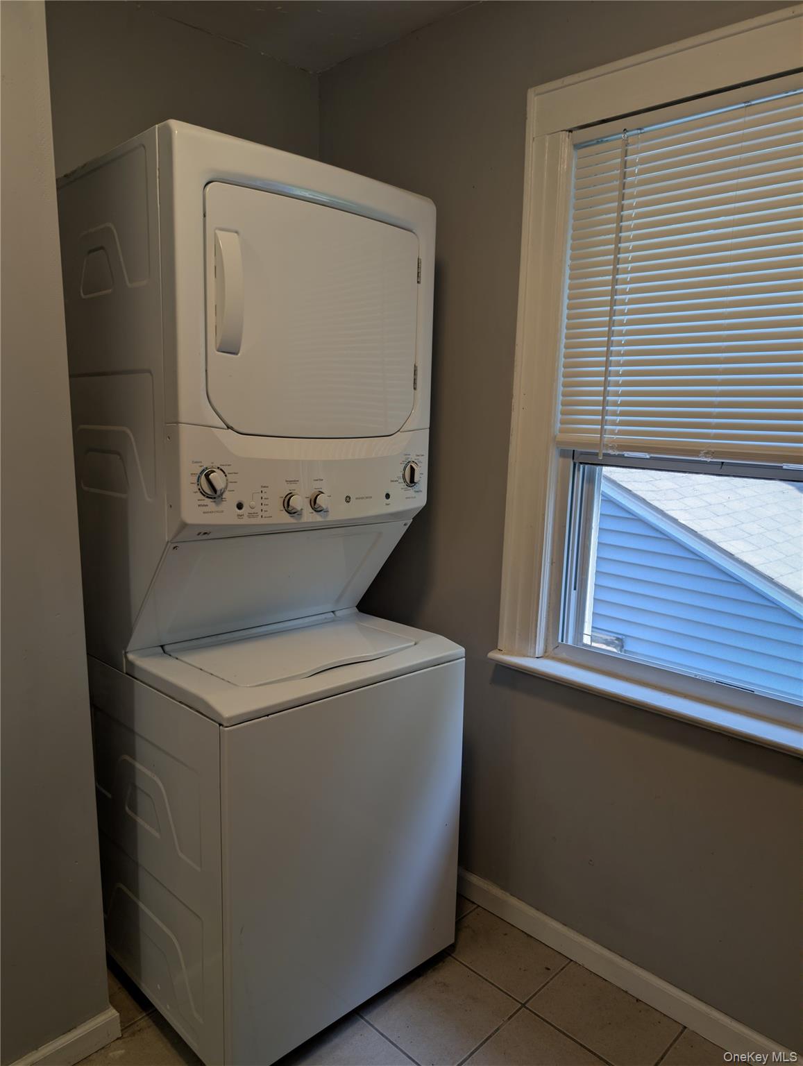 394 Riley Road, Unit 1 New Windsor, NY 12553 - Photo 15 of 24 Dedicated laundry area features a stacked washer and dryer unit, tiled flooring, painted walls, and a window with blinds
