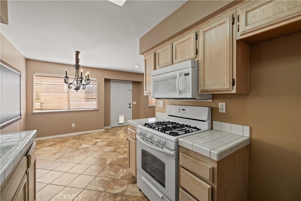 43413 30th Street West, Unit 3 Lancaster, CA 93536 - Photo 15 of 38 a kitchen with granite countertop a stove a sink dishwasher and a microwave