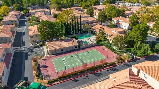 an aerial view of a tennis ground with large trees and buildings