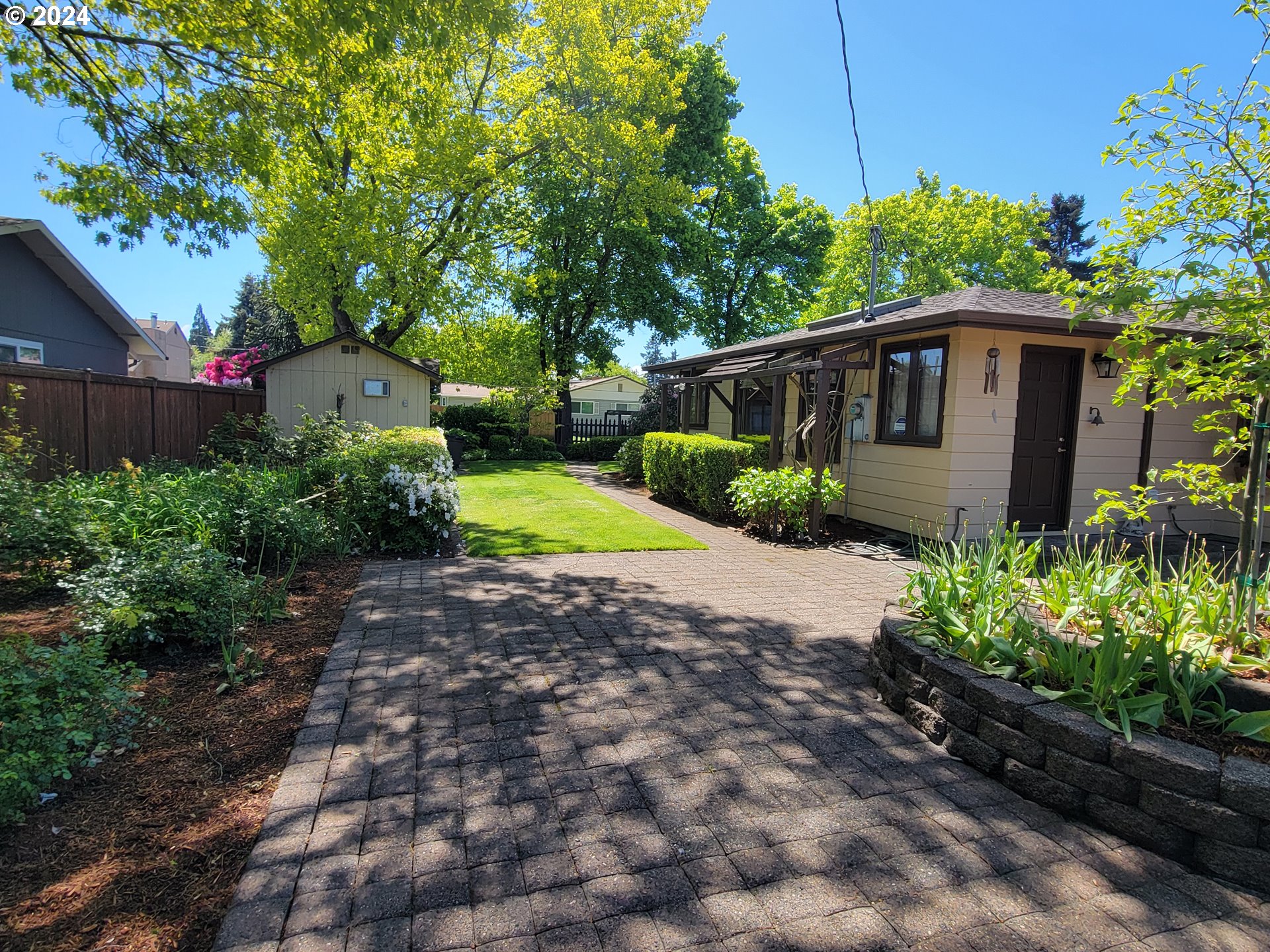 2565 Newcastle Street Eugene, OR 97404 - Photo 10 of 38 a yellow house with flower garden in front of it