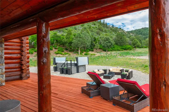 a view of deck with table and chairs under wooden roof with potted plants