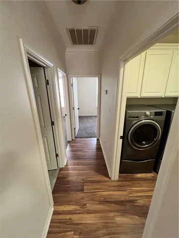 a view of a hallway with wooden floor and washer