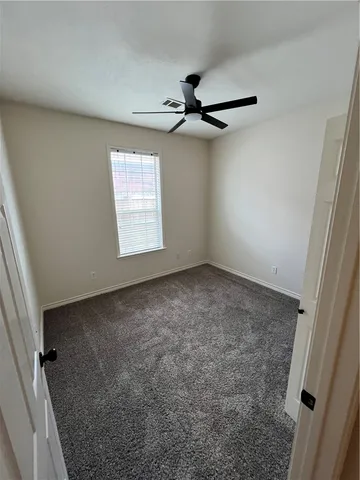 an empty room with a window and a fan