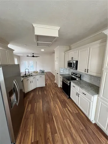 a kitchen with a refrigerator wooden floor and white cabinets
