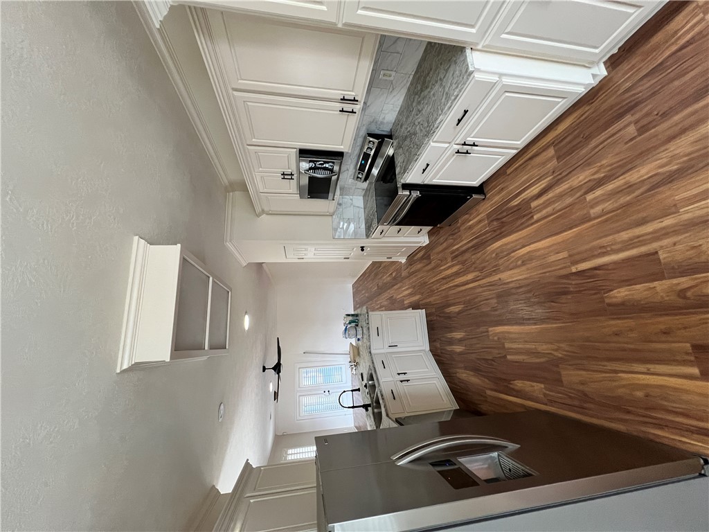 2619 Trophy Drive Bryan, TX 77802 - Photo 9 of 25 a kitchen with a refrigerator wooden floor and white cabinets