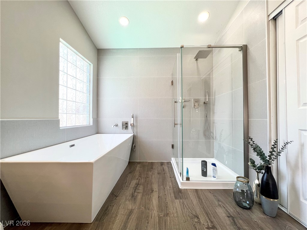 2218 Armacost Drive Henderson, NV 89074 - Photo 13 of 31 Full bathroom with tile walls, a shower stall, a soaking tub, dark wood-style flooring, and recessed lighting