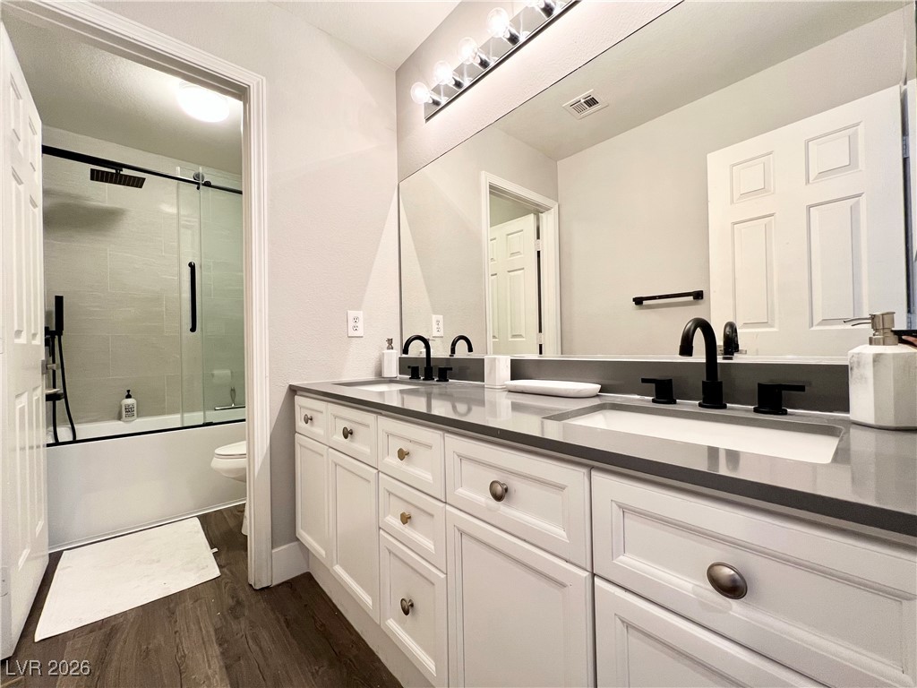 2218 Armacost Drive Henderson, NV 89074 - Photo 15 of 31 Bathroom with double vanity, shower / bath combination with glass door, and dark wood-type flooring