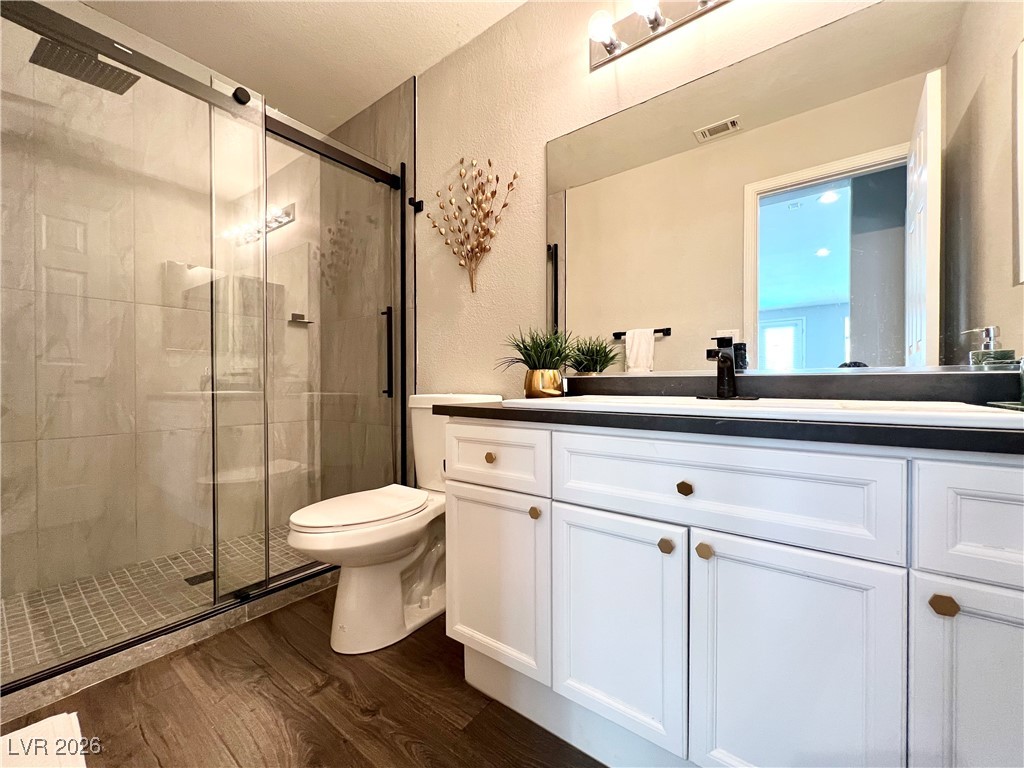 2218 Armacost Drive Henderson, NV 89074 - Photo 18 of 31 Bathroom featuring a shower stall, dark wood finished floors, vanity, and a textured wall