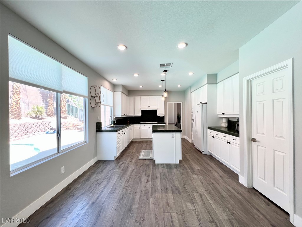 2218 Armacost Drive Henderson, NV 89074 - Photo 5 of 31 Kitchen featuring dark countertops, hanging light fixtures, white cabinets, a kitchen island, and dark wood-type flooring