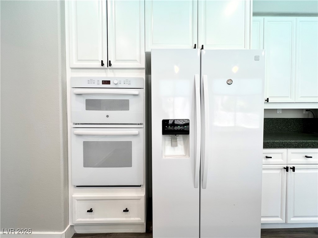 2218 Armacost Drive Henderson, NV 89074 - Photo 6 of 31 Kitchen with white appliances, white cabinetry, and dark wood-style flooring