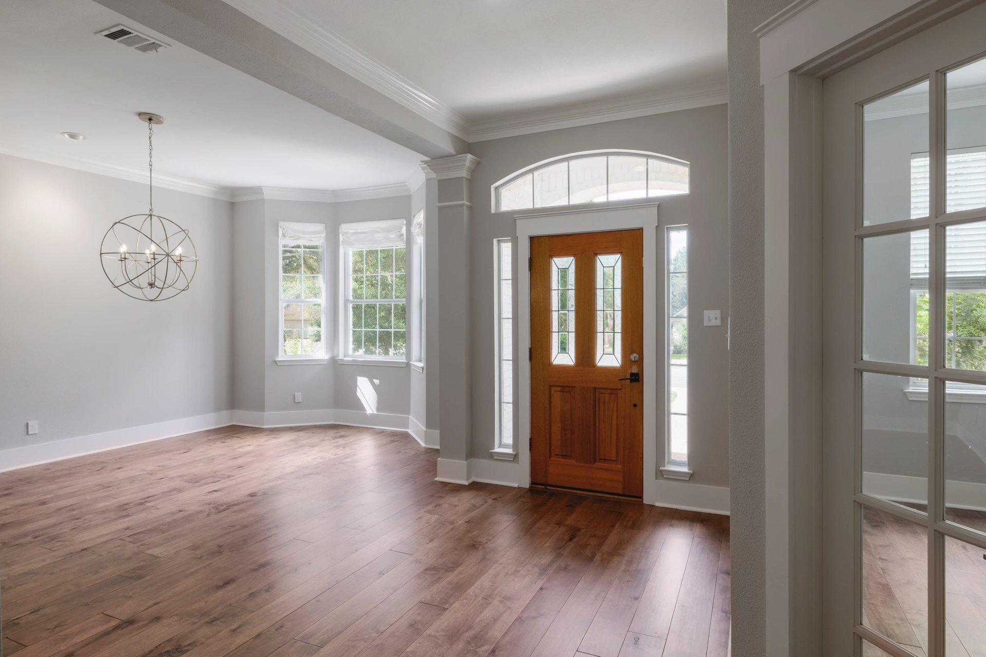 5512 Ballenton Lane Austin, TX 78739 - Photo 5 of 40 Hardwood floors stretch across this inviting space, illuminated by a decorative chandelier and ample natural light.