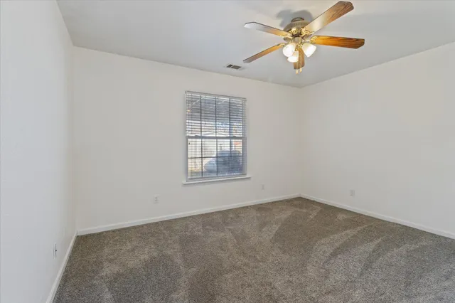 an empty room with a window and a fan