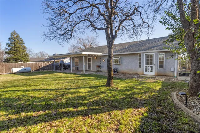 a large pool that has lawn chairs under an tree