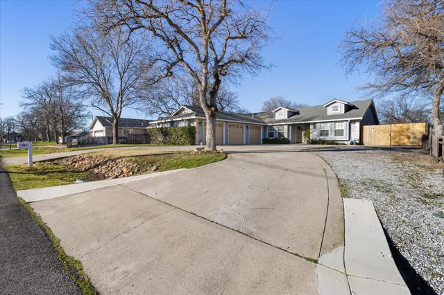 a view of a large white house with a big yard and large trees