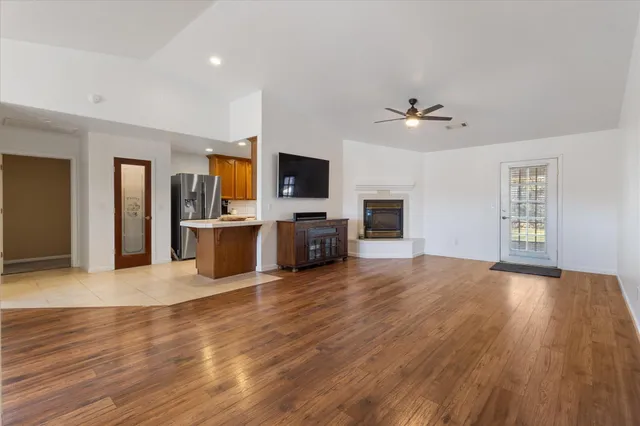 a view of a livingroom with a flat screen tv wooden floor and a ceiling fan