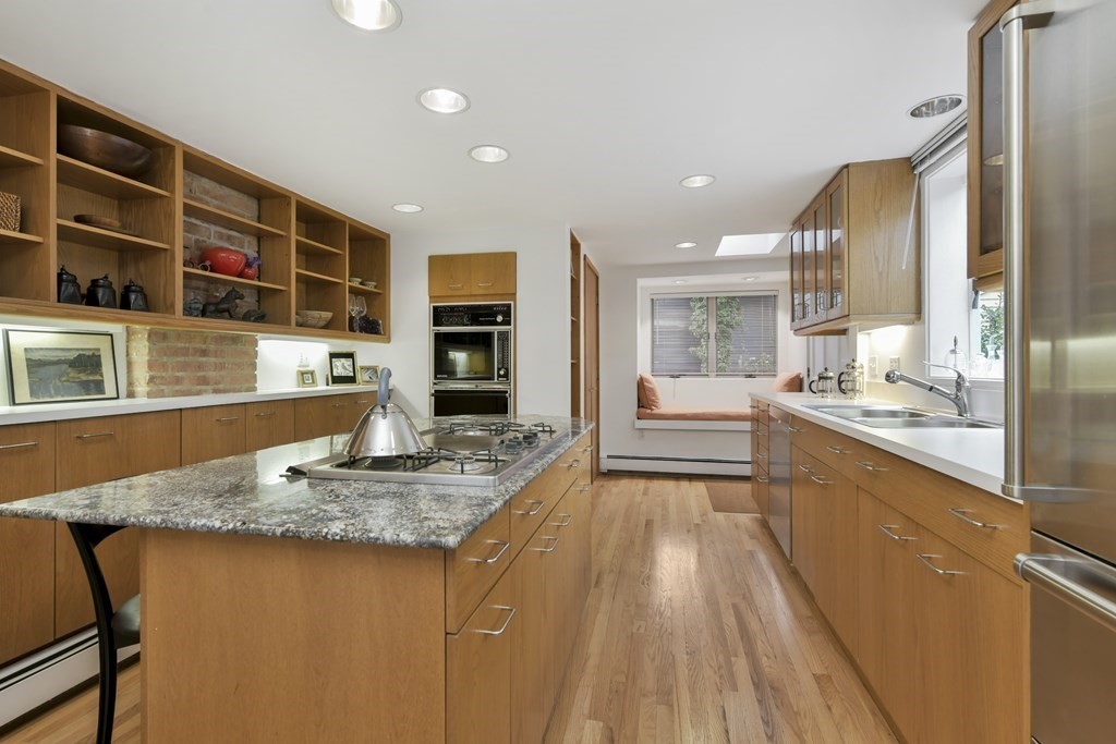 a large kitchen with kitchen island a large counter top stainless steel appliances and cabinets