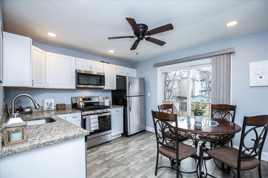 30 Eleanor Street Chelsea, MA 02150 - Photo 6 of 23 a kitchen with stainless steel appliances granite countertop white cabinets a sink a stove a dining table and chairs