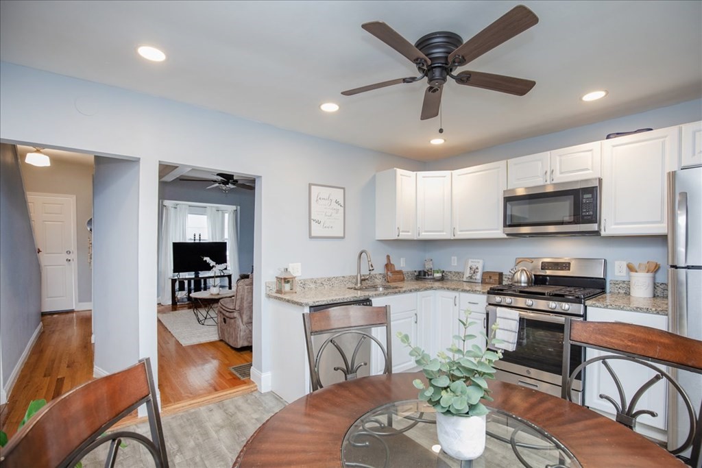 30 Eleanor Street Chelsea, MA 02150 - Photo 7 of 23 a kitchen with stainless steel appliances granite countertop a stove a sink dishwasher a dining table and chairs with wooden floor