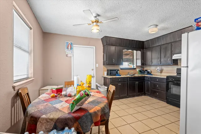 a kitchen with stainless steel appliances kitchen island granite countertop a sink dishwasher a stove a refrigerator with a dining table and chairs with wooden floor