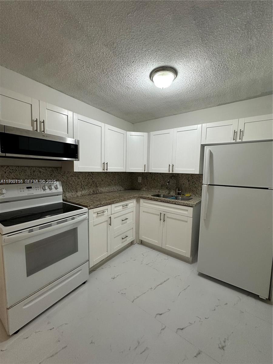 1733 Mayo Street, Unit 2 Hollywood, FL 33020 - Photo 3 of 10 a kitchen with granite countertop white cabinets and white appliances