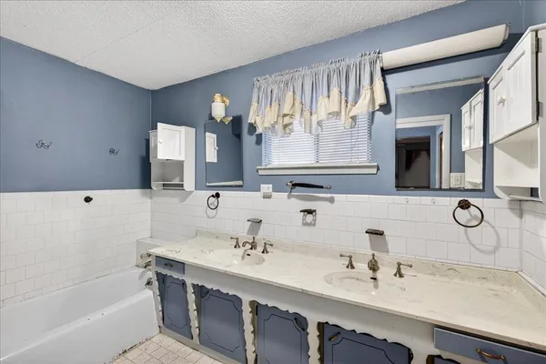 a bathroom with a double vanity sink mirror and bathtub