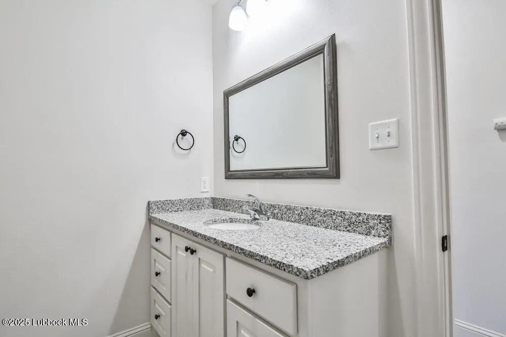 1602 102nd Street Lubbock, TX 79423 - Photo 13 of 16 a bathroom with a granite countertop sink and a mirror