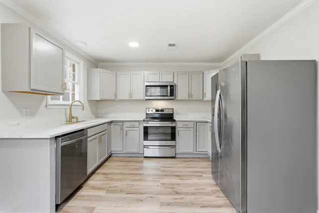 a kitchen with granite countertop a refrigerator and a stove top oven