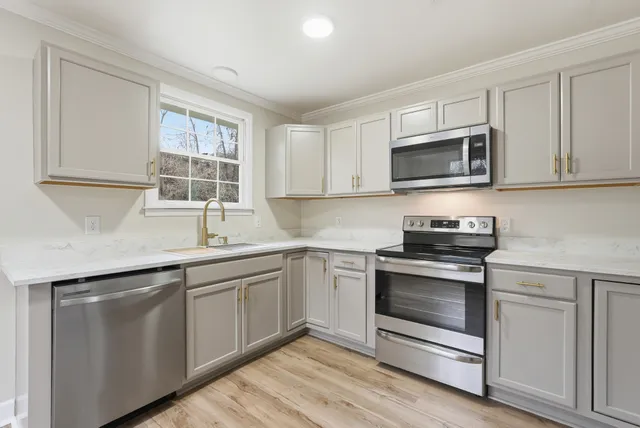 a kitchen with white cabinets appliances and a sink