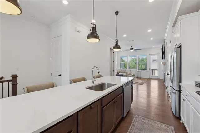 a kitchen with stainless steel appliances granite countertop a sink a refrigerator and a wooden floor