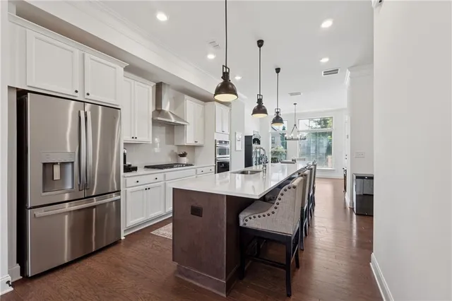 a kitchen with stainless steel appliances granite countertop a refrigerator a sink dishwasher a stove and a refrigerator with wooden floor