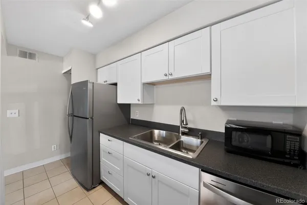 a kitchen with stainless steel appliances granite countertop white cabinets a refrigerator and a sink