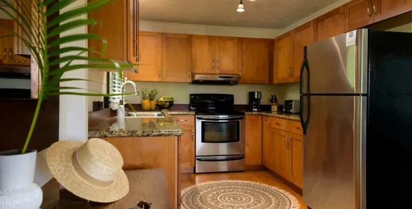 a kitchen with stainless steel appliances granite countertop a refrigerator a sink dishwasher a stove top oven a washer and dryer with wooden floor