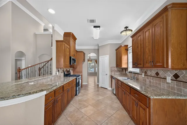 a kitchen with stainless steel appliances granite countertop a sink a stove and cabinets