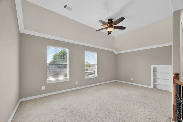 an empty room with chandelier fan and windows