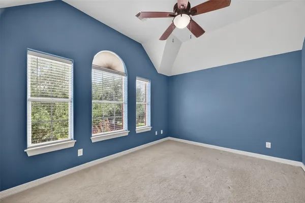 a view of an empty room with chandelier fan and a window