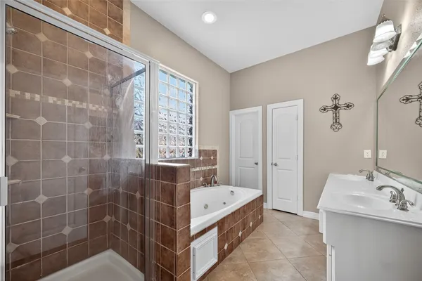 a bathroom with a tub sink double vanity and a mirror