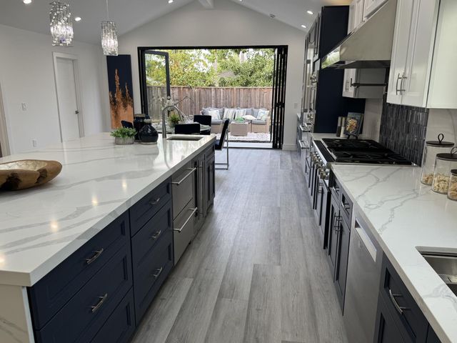 a kitchen with kitchen island a large counter space a sink a window and stainless steel appliances