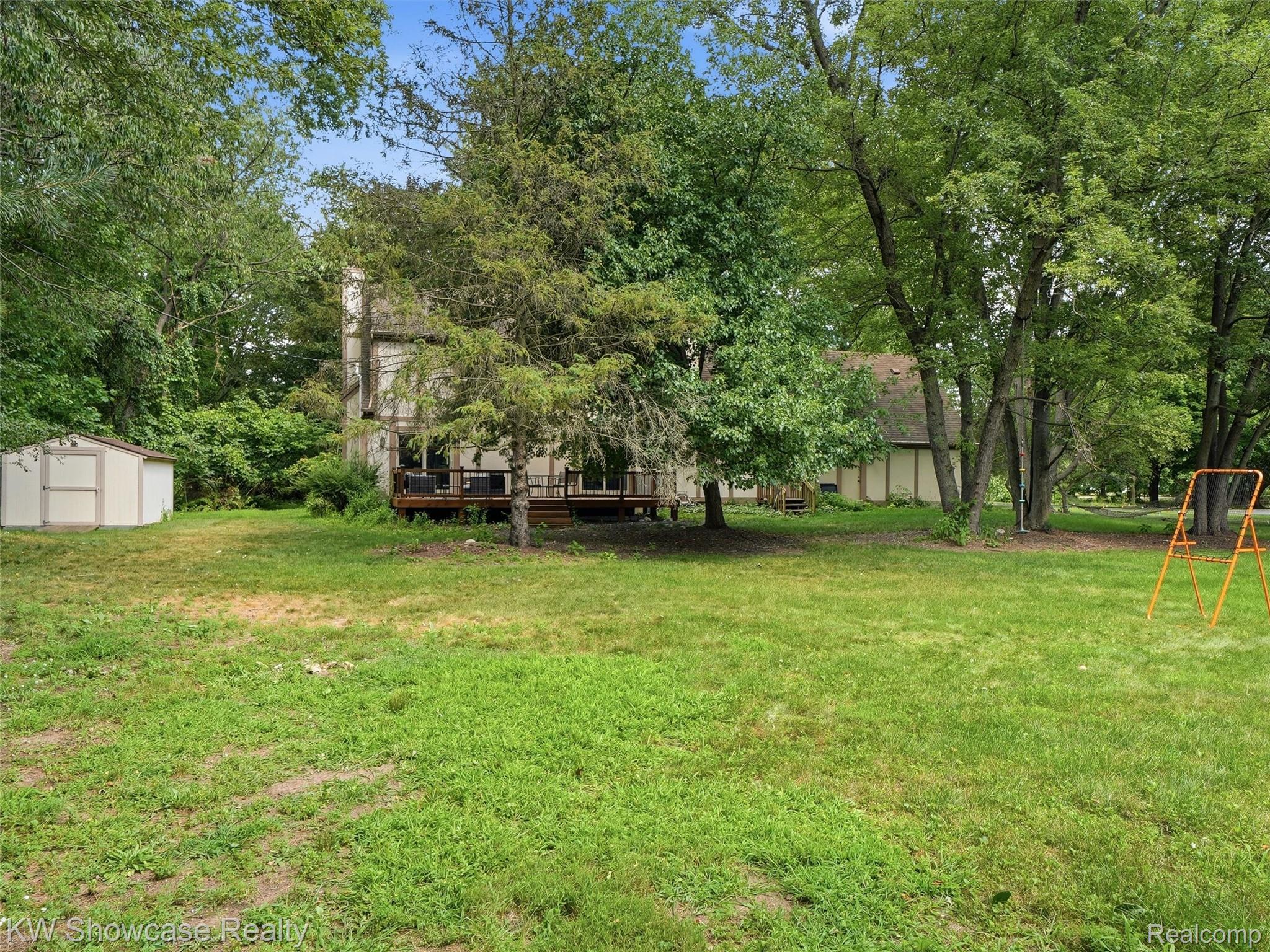 3360 Pleasant Valley Road Brighton, MI 48114 - Photo 47 of 60 Spacious backyard featuring a two-story residence with a multi-level deck, a detached storage shed, and mature trees providing natural screening