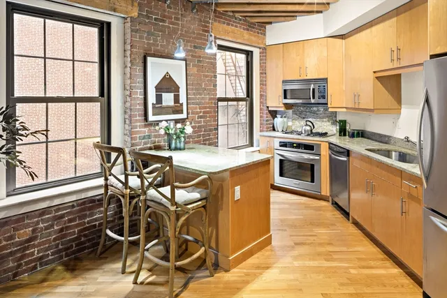 a kitchen with stainless steel appliances granite countertop a stove top oven a sink dishwasher a dining table and chairs with wooden floor