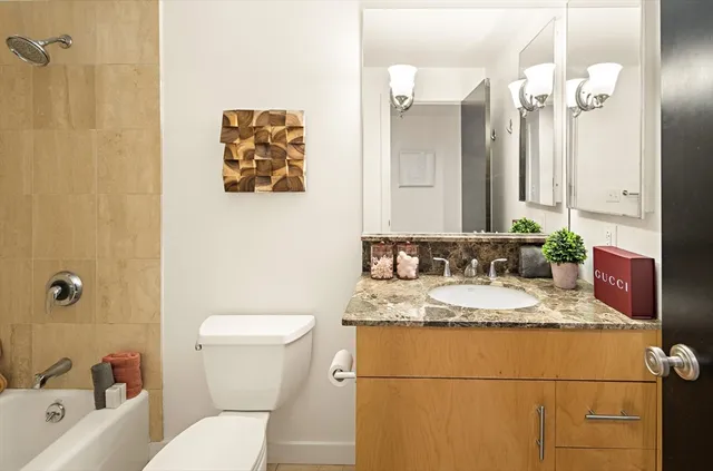 a bathroom with a granite countertop sink mirror vanity and toilet