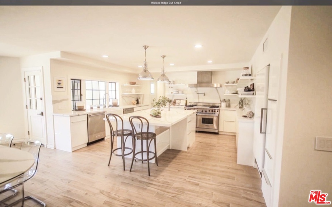 1075 Wallace Ridge Beverly Hills, CA 90210 - Photo 12 of 35 a kitchen with stainless steel appliances kitchen island granite countertop a table chairs microwave and sink
